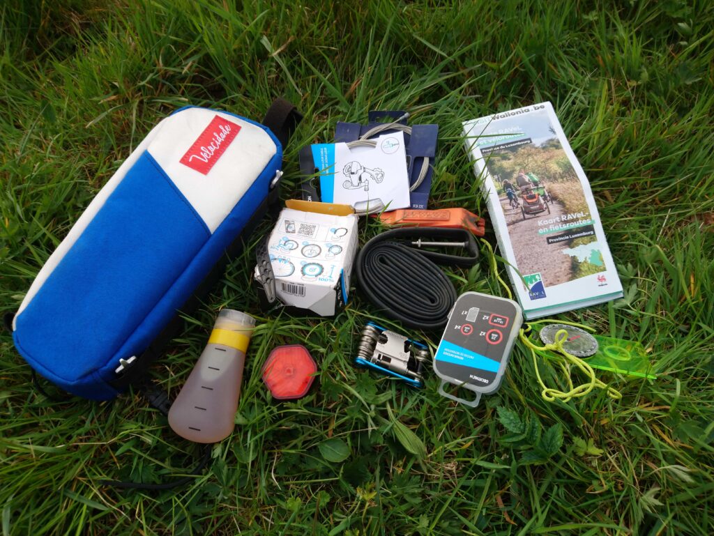 Bikepacking en image.
Photo de la sacoche top-tube avec les affaires étalées sur la pelouse.